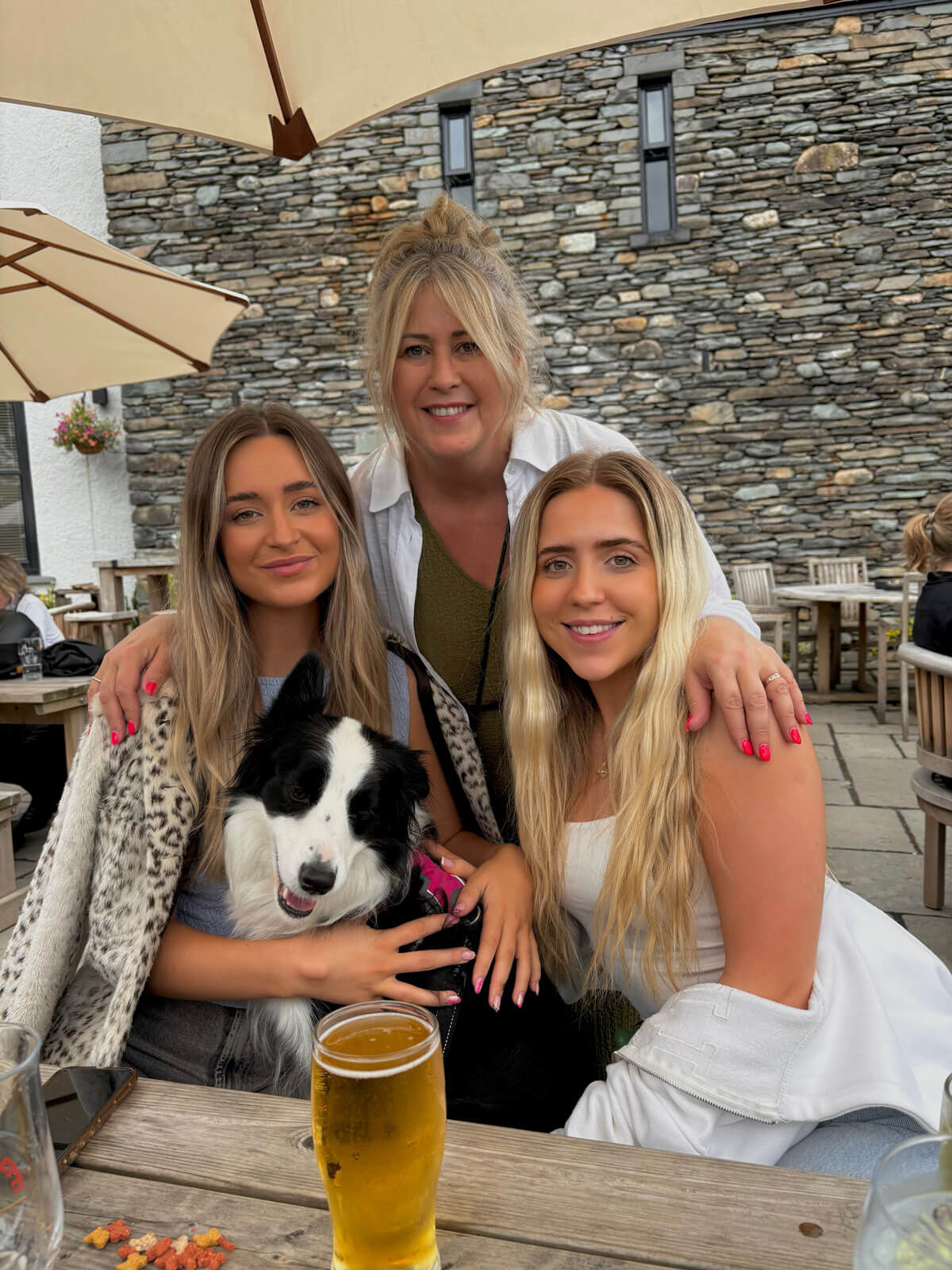 three women smiling at camera with a dog