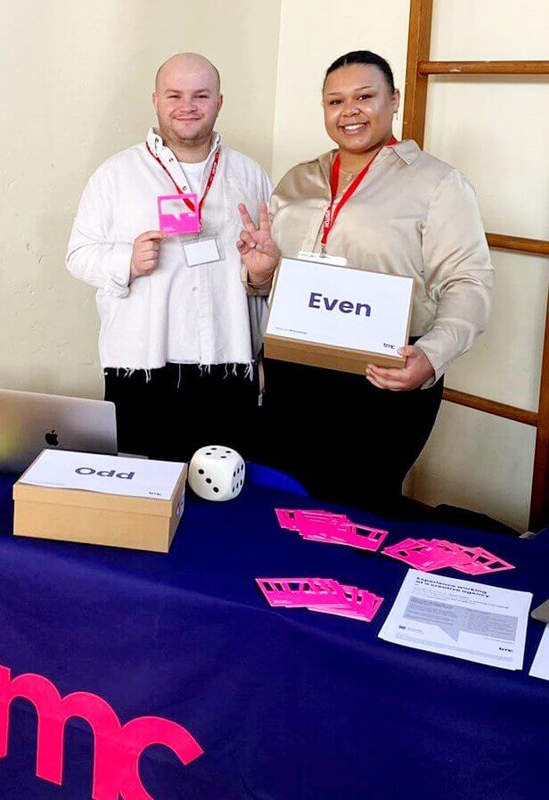 A man and a woman are standing at an event table