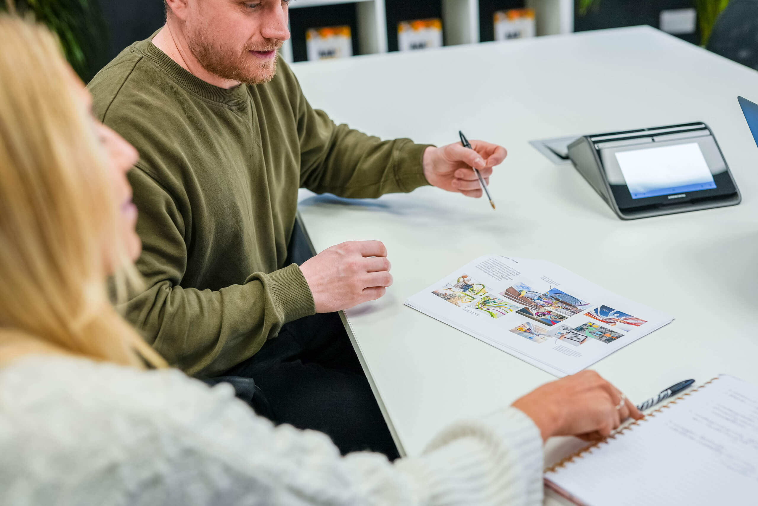 One male, one female discussing a storyboard around a meeting room table. - video production