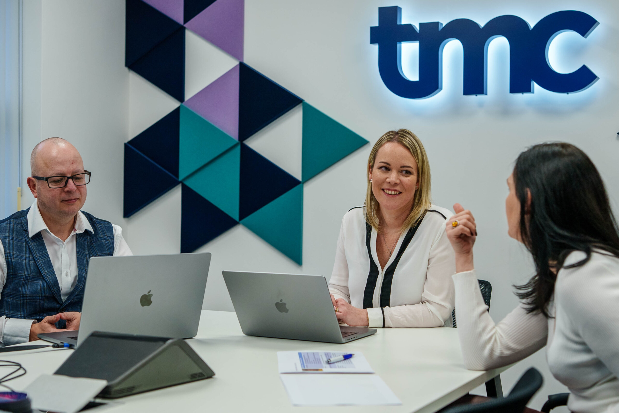 TMC service team. En mand og to kvinder der taler sammen i et møde format.