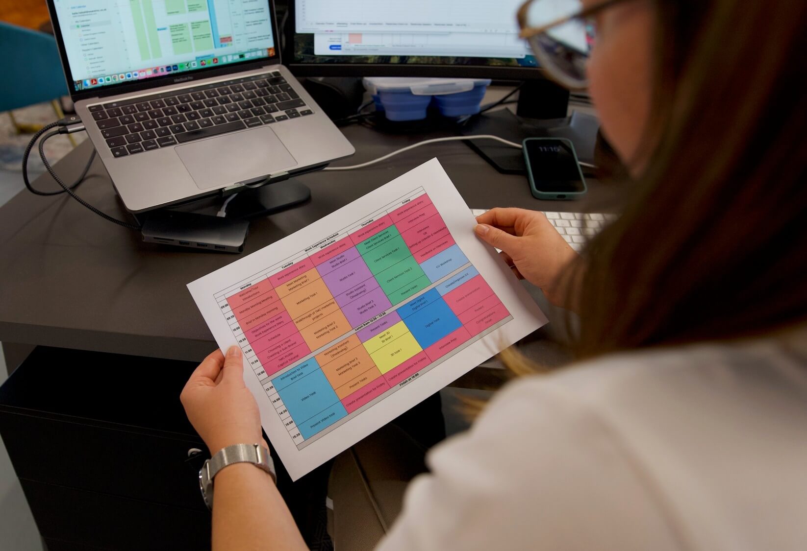 Work experience schedule held by person infront of laptop