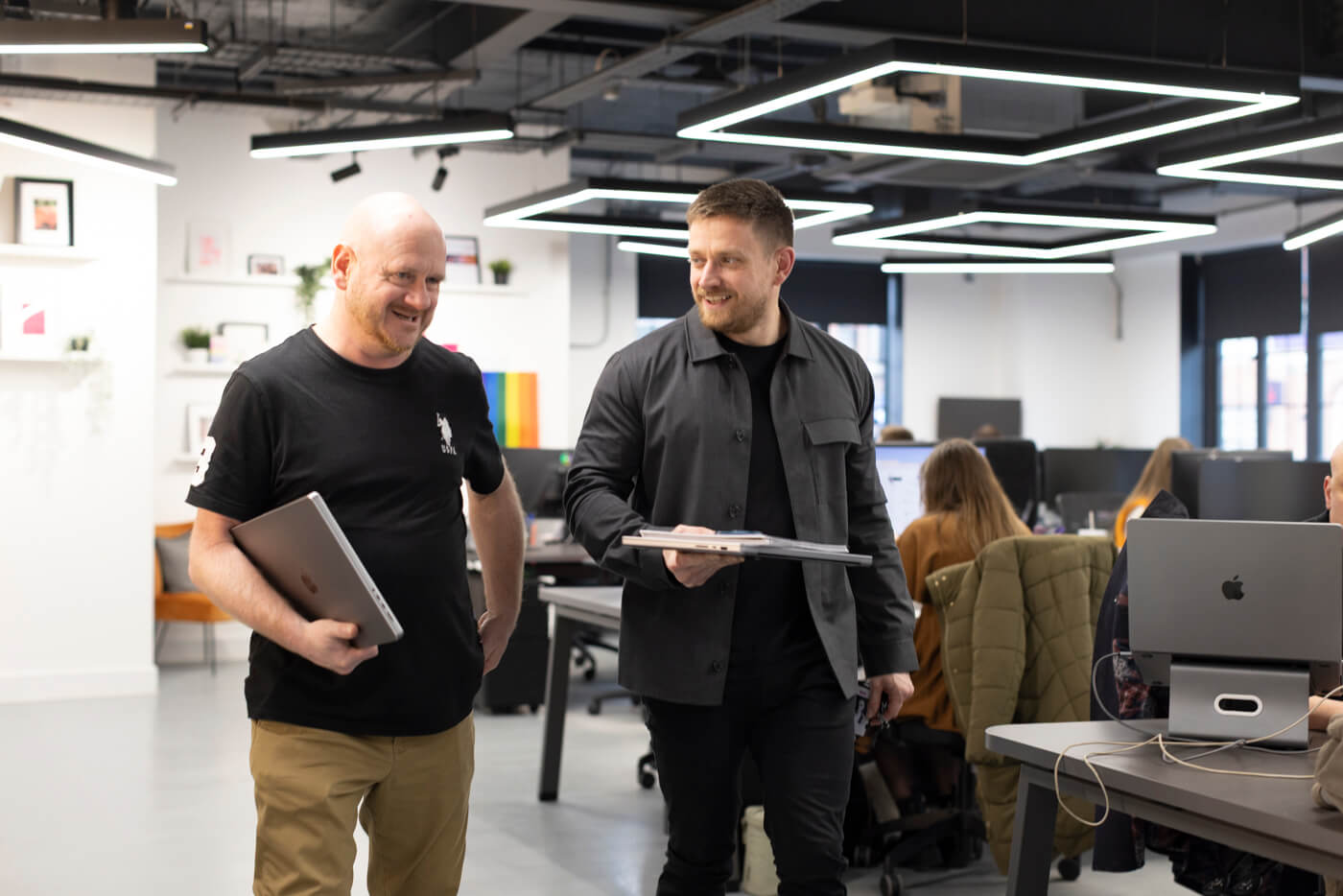 two men walking with laptops